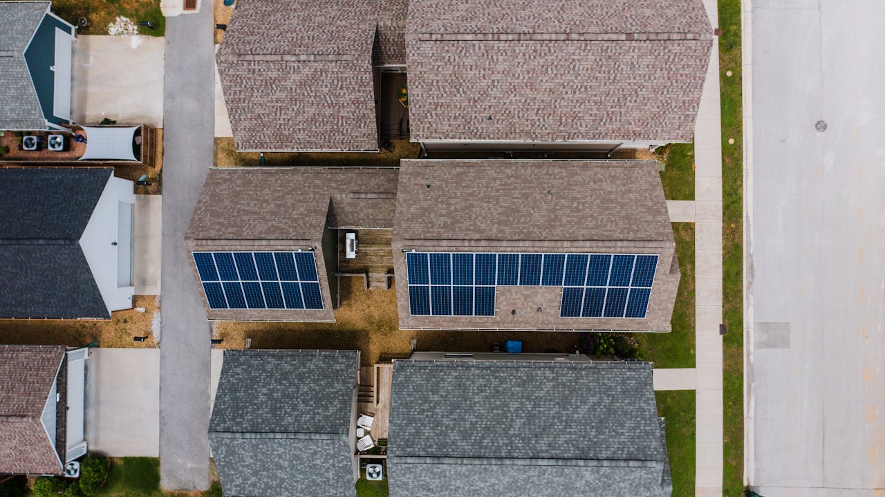 Top-down view of suburban houses featuring solar panels on roofs, showcasing renewable energy use.